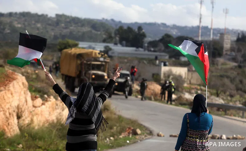 Palestinian girls holds a poster of Hatem Shadid (L) who killed by Israeli soldier (R), during clashes following a demonstration against the expropriation of Palestinian land by Israel in the West Bank village of Nabi Sa...