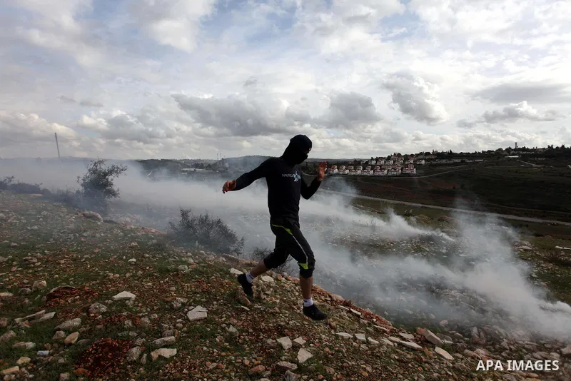 A Palestinian protester runs from tear gas during clashes following a demonstration against the expropriation of Palestinian land by Israel in the West Bank village of Nabi Saleh on December 7, 2012. Photo by Issam Rimaw...