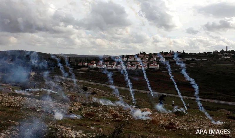 A Palestinian protester runs from tear gas during clashes following a demonstration against the expropriation of Palestinian land by Israel in the West Bank village of Nabi Saleh on December 7, 2012. Photo by Issam Rimaw...