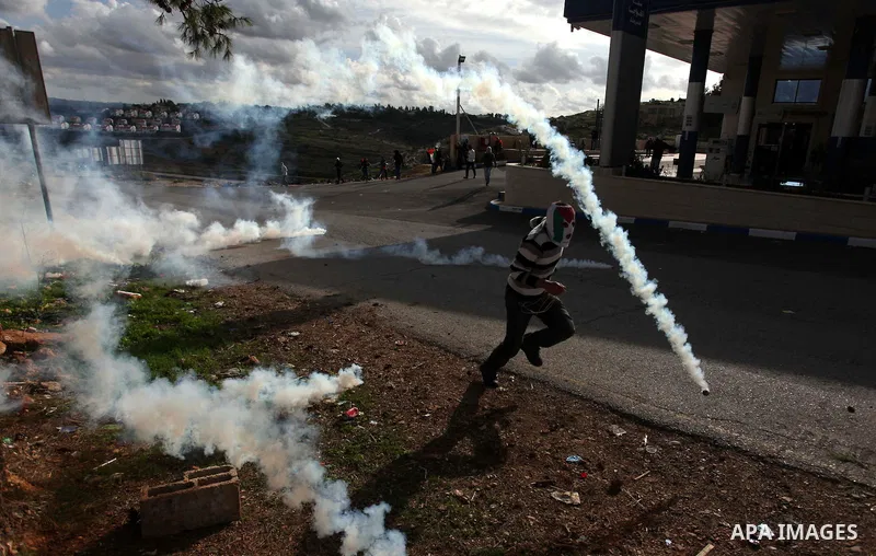 A Palestinian protester runs from tear gas during clashes following a demonstration against the expropriation of Palestinian land by Israel in the West Bank village of Nabi Saleh on December 7, 2012. Photo by Issam Rimaw...