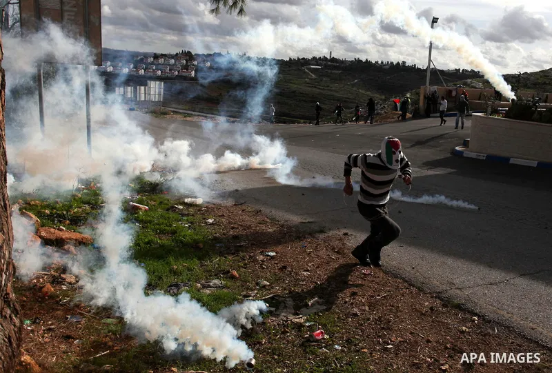 A Palestinian protester runs from tear gas during clashes following a demonstration against the expropriation of Palestinian land by Israel in the West Bank village of Nabi Saleh on December 7, 2012. Photo by Issam Rimaw...