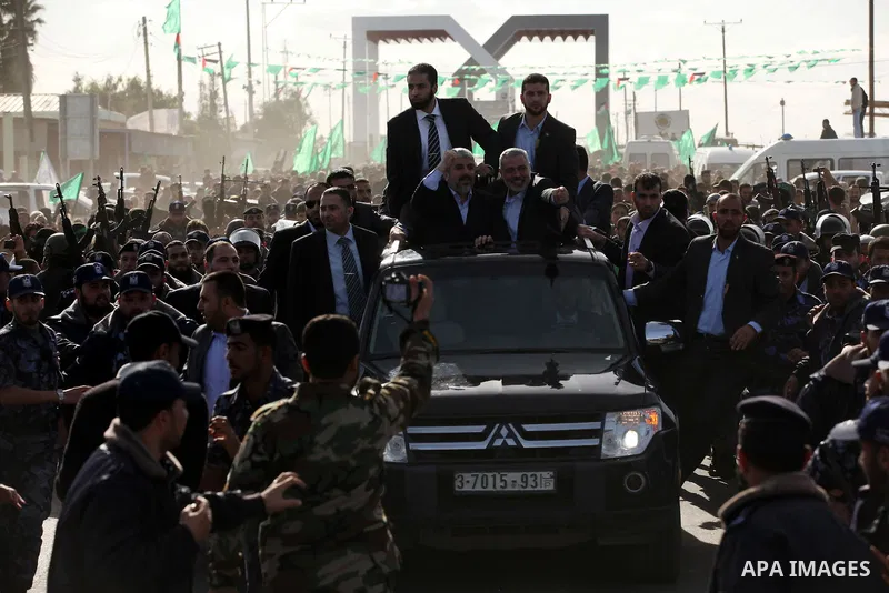 Hamas chief Khaled Meshaal waves to the crowd from his car beside senior Hamas leader Ismail Haniyeh at the Rafah Crossing, in southern Gaza Strip December 7, 2012. Meshaal ended decades of exile from Palestinian land on...