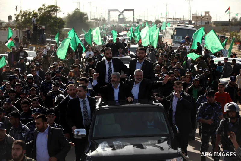 Hamas chief Khaled Meshaal waves to the crowd from his car beside senior Hamas leader Ismail Haniyeh at the Rafah Crossing, in southern Gaza Strip December 7, 2012. Meshaal ended decades of exile from Palestinian land on...