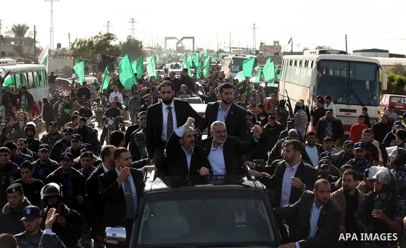 Hamas chief Khaled Meshaal waves to the crowd from his car beside senior Hamas leader Ismail Haniyeh at the Rafah Crossing, in southern Gaza Strip December 7, 2012. Meshaal ended decades of exile from Palestinian land on...