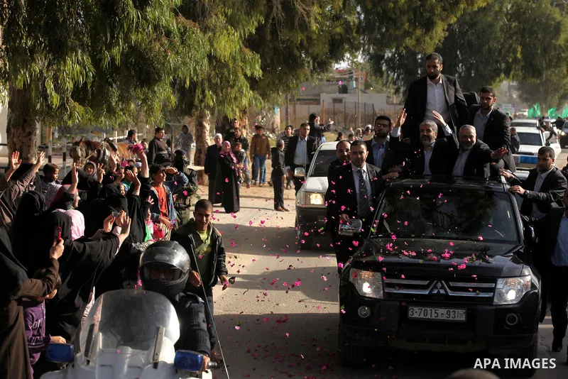 Hamas chief Khaled Meshaal waves to the crowd from his car beside senior Hamas leader Ismail Haniyeh at the Rafah Crossing, in southern Gaza Strip December 7, 2012. Meshaal ended decades of exile from Palestinian land on...