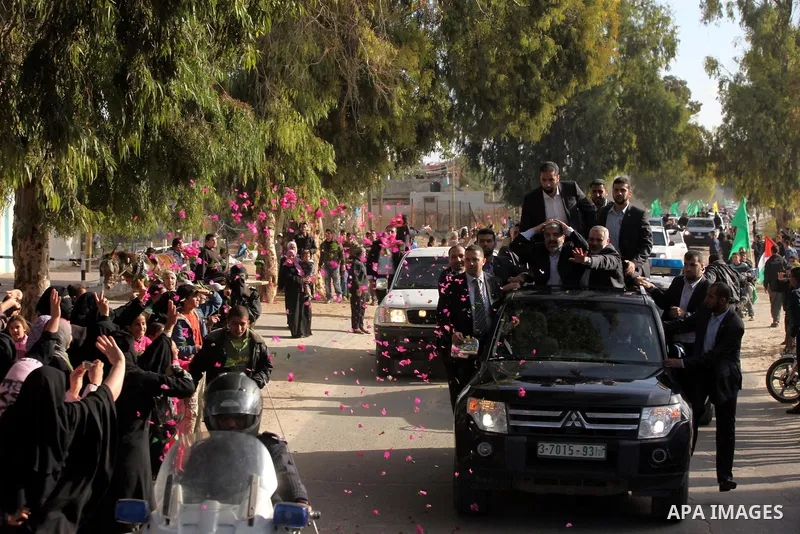 Hamas chief Khaled Meshaal waves to the crowd from his car beside senior Hamas leader Ismail Haniyeh at the Rafah Crossing, in southern Gaza Strip December 7, 2012. Meshaal ended decades of exile from Palestinian land on...