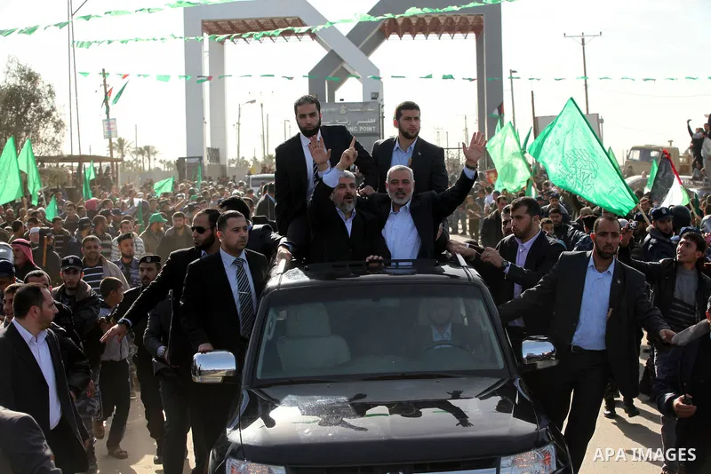 Hamas chief Khaled Meshaal waves to the crowd from his car beside senior Hamas leader Ismail Haniyeh at the Rafah Crossing, in southern Gaza Strip December 7, 2012. Meshaal ended decades of exile from Palestinian land on...