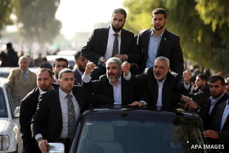 Hamas chief Khaled Meshaal waves to the crowd from his car beside senior Hamas leader Ismail Haniyeh at the Rafah Crossing, in southern Gaza Strip December 7, 2012. Meshaal ended decades of exile from Palestinian land on...