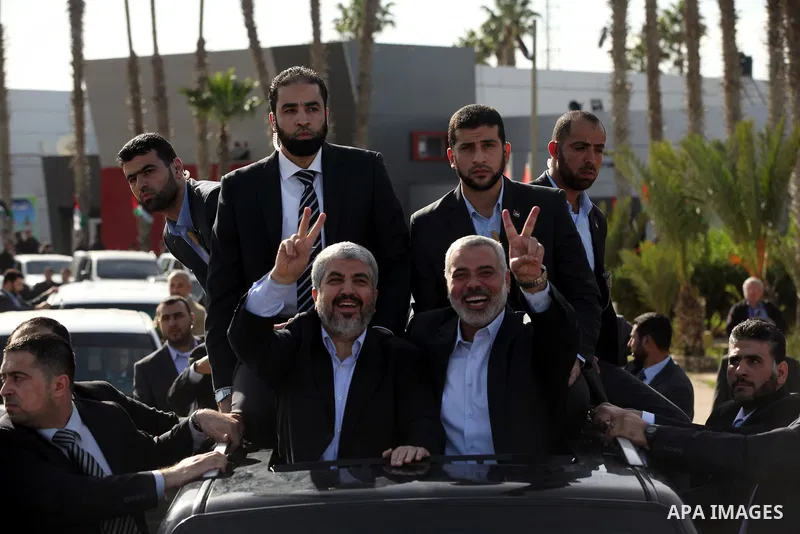 Hamas chief Khaled Meshaal waves to the crowd from his car beside senior Hamas leader Ismail Haniyeh at the Rafah Crossing, in southern Gaza Strip December 7, 2012. Meshaal ended decades of exile from Palestinian land on...