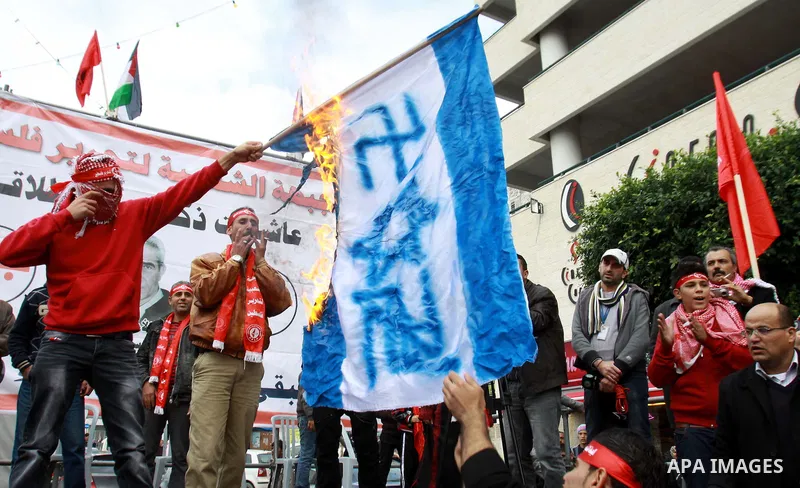 A Palestinian protester burn israeli flag, and hold up banners and portraits during a rally to mark the 45th anniversary of the establishment of the PFLP in the West Bank city of Nablus on December 8, 2012. Photo by Neda...