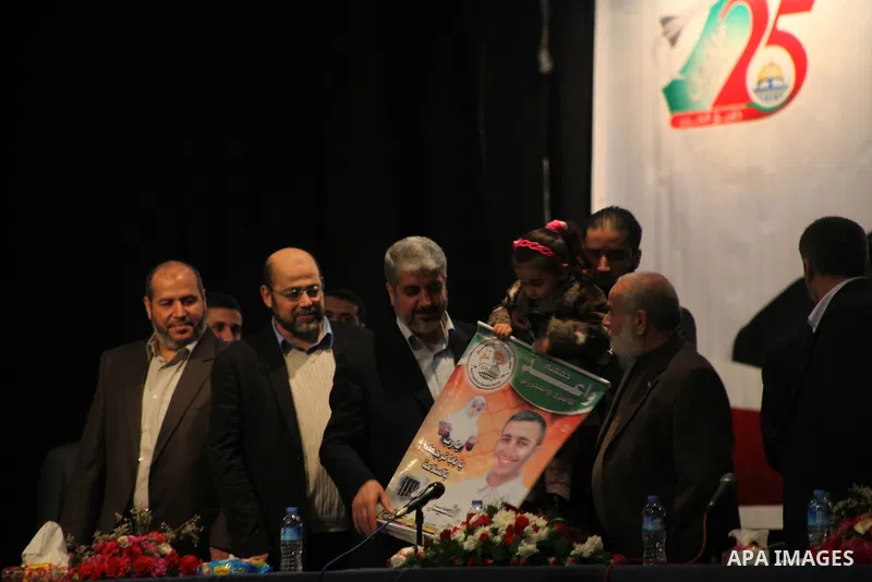 Hamas chief Khaled Meshaal, hold a protrait of a Palestinian prisoner during a meeting with the relatives of prisoners in Israeli jails in Gaza City December 9, 2012. Meshaal, in a defiant speech during his first ever vi...