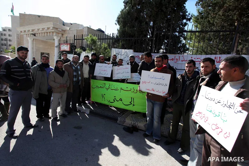 Palestinian teachers and graduates who were barred from employment by Ministry of Education, hold placards during a protest in front of Council of Ministers, in the West Bank city of Ramallah, December 09, 2012 . Photo b...