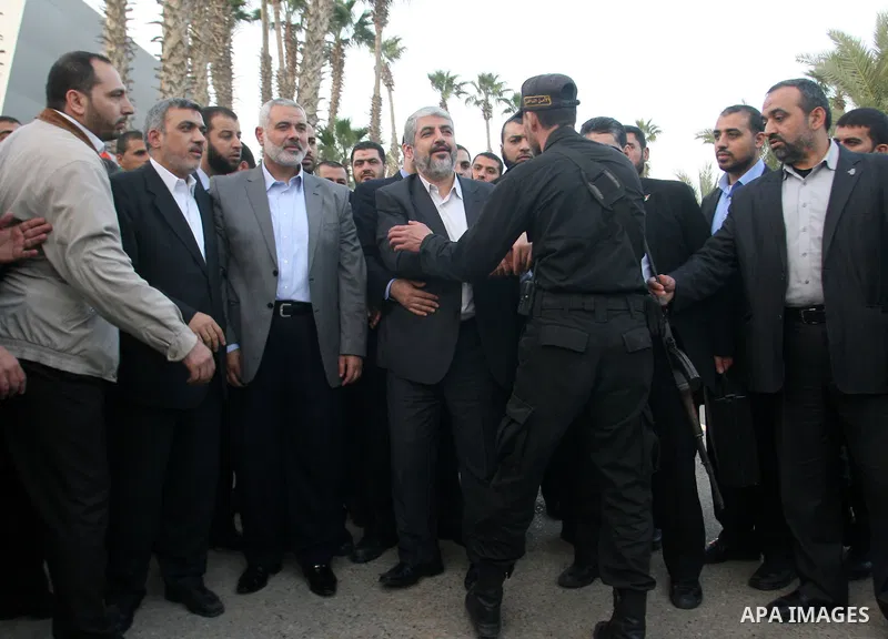 A Palestinian policeman shakes hands with Hamas leader in exile Khaled Meshaal, upon his departure from the Gaza Strip on December 10, 2012 in Rafah, on the border with Egypt. Exiled Hamas chief Khaled Meshaal left Gaza...