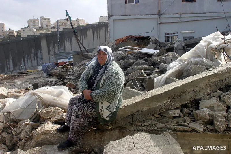 A Palestinian woman from Jabari family sits on the rubble of their house after it was demolished by Jerusalem municipality workers in the mostly Arab east Jerusalem neighborhood of al-Tur on December 11, 2012. Palestinia...