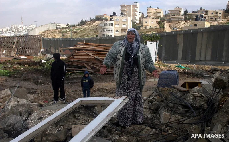 Member of the Palestinian Jabari family are seen close to the rubble of their house after it was demolished by Jerusalem municipality workers in the mostly Arab east Jerusalem neighborhood of al-Tur on December 11, 2012....
