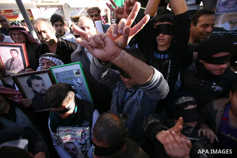 Protesters hold portraits of Samer Issawi and Ayman Sharwanah, Palestinian prisoners held in Israeli jails and on hunger strike, during a solidarity protest in the West Bank city of Hebron, December 12, 2012. Demonstrato...