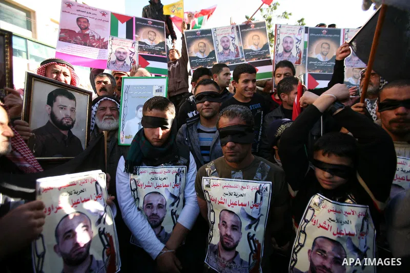 Protesters hold portraits of Samer Issawi and Ayman Sharwanah, Palestinian prisoners held in Israeli jails and on hunger strike, during a solidarity protest in the West Bank city of Hebron, December 12, 2012. Demonstrato...