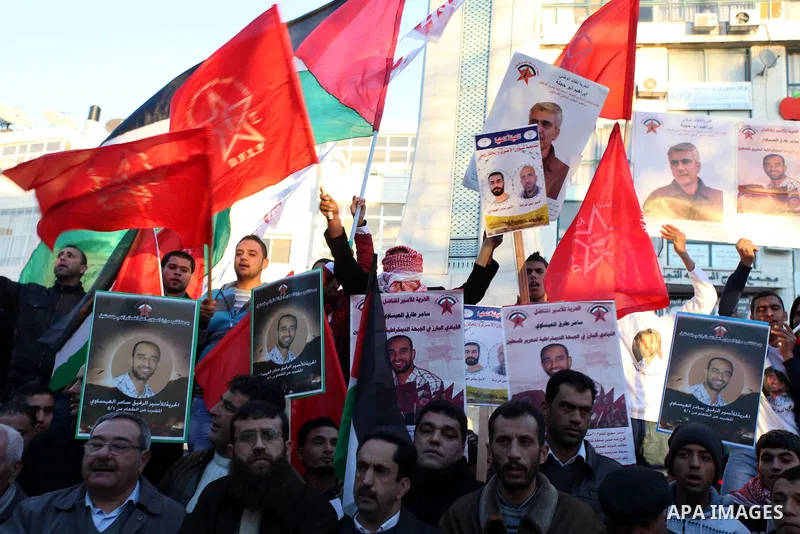 Protesters hold portraits of Samer Issawi, A Palestinian prisoner held in Israeli jail and on hunger strike, during a solidarity protest in the West Bank city of Ramallah, December 12, 2012. Demonstrators protested in so...