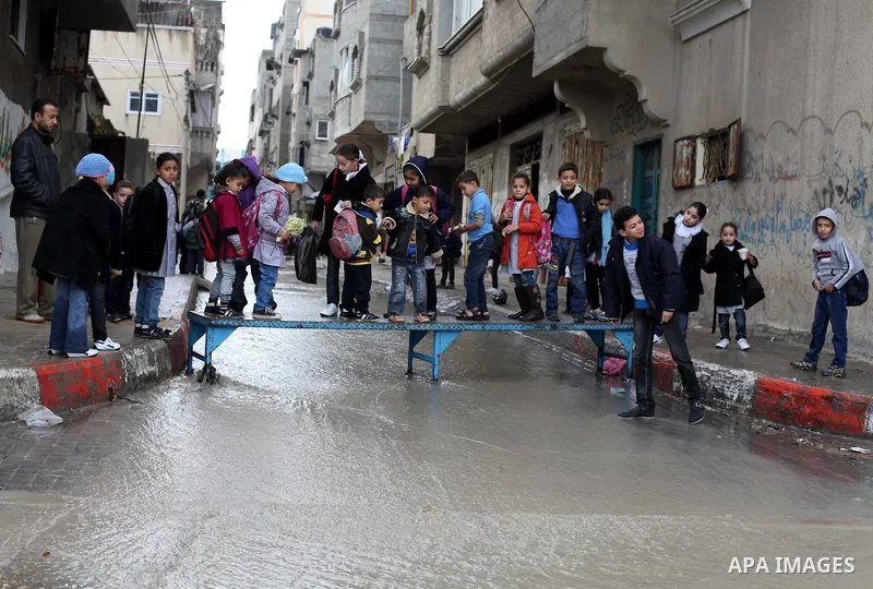 Palestinians cross a flooded street in al-Shatee refugee camp in Gaza City on Dec. 13, 2012. Palestinian refugees in Gaza camps need more support to reconstruct Gaza, promote economic recovery and address the long-term d...