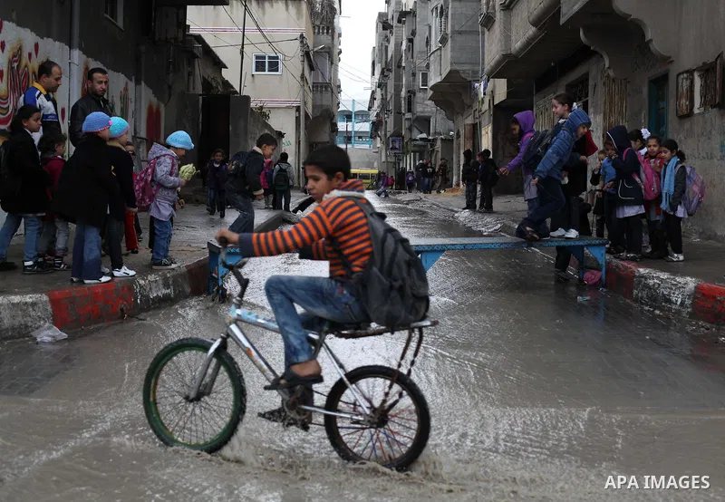 Palestinians cross a flooded street in al-Shatee refugee camp in Gaza City on Dec. 13, 2012. Palestinian refugees in Gaza camps need more support to reconstruct Gaza, promote economic recovery and address the long-term d...