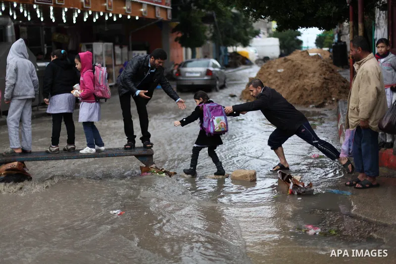 Palestinians cross a flooded street in al-Shatee refugee camp in Gaza City on Dec. 13, 2012. Palestinian refugees in Gaza camps need more support to reconstruct Gaza, promote economic recovery and address the long-term d...