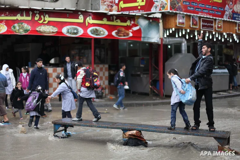 Palestinians cross a flooded street in al-Shatee refugee camp in Gaza City on Dec. 13, 2012. Palestinian refugees in Gaza camps need more support to reconstruct Gaza, promote economic recovery and address the long-term d...