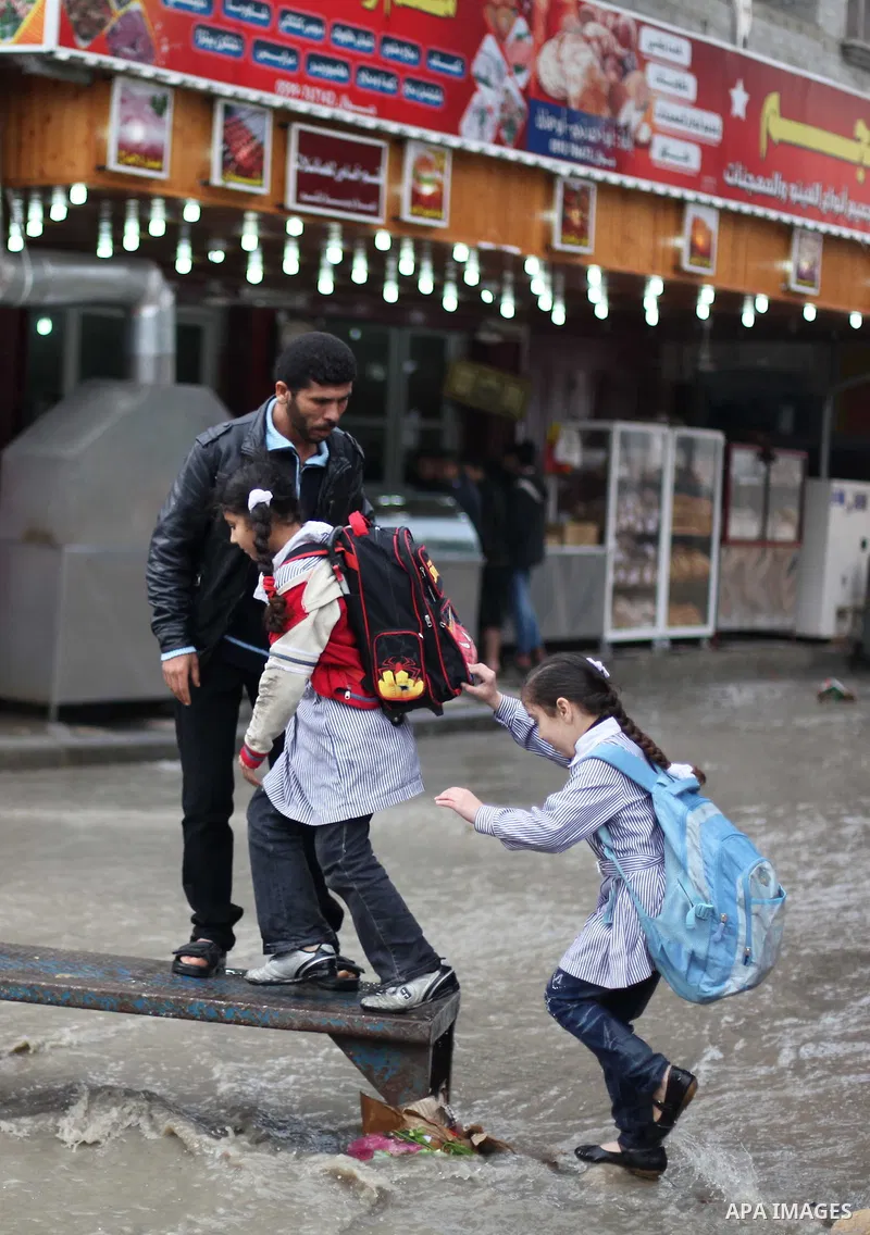 Palestinians cross a flooded street in al-Shatee refugee camp in Gaza City on Dec. 13, 2012. Palestinian refugees in Gaza camps need more support to reconstruct Gaza, promote economic recovery and address the long-term d...
