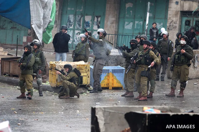 Israeli soldiers shoot a tear gas grenade at Palestinian protesters during clashes in the West Bank city of Hebron, 13 December 2012. The clashes broke out before the funeral of Palestinian teenager Mohammed Ziad Salayme...