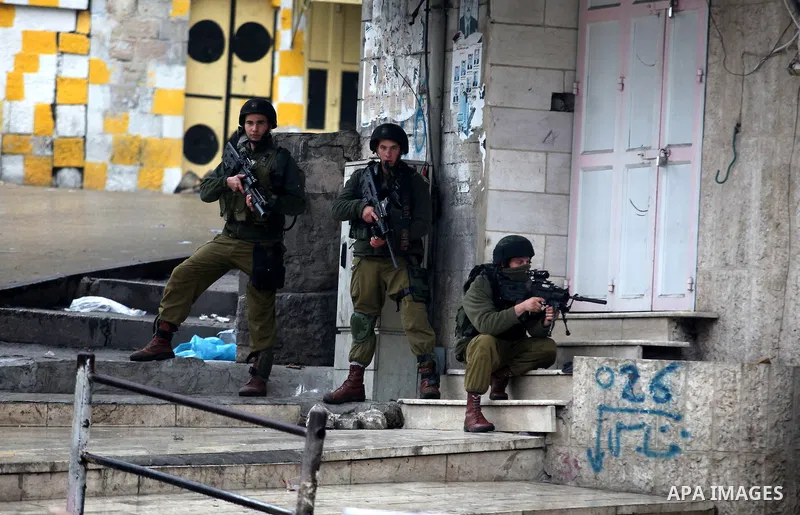 An Israeli soldier shoots a tear gas grenade at Palestinian protesters during clashes in the West Bank city of Hebron, 13 December 2012. The clashes broke out before the funeral of Palestinian teenager Mohammed Ziad Sala...
