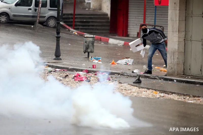A Palestinian protester covers from tear gas shoot by Israeli soldiers during clashes in the West Bank city of Hebron, 13 December 2012. The clashes broke out before the funeral of Palestinian teenager Mohammed Ziad Sala...