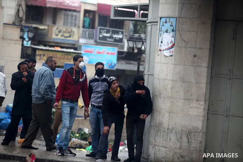 Palestinian protesters cover from tear gas shoot by Israeli soldiers during clashes in the West Bank city of Hebron, 13 December 2012. The clashes broke out before the funeral of Palestinian teenager Mohammed Ziad Salaym...