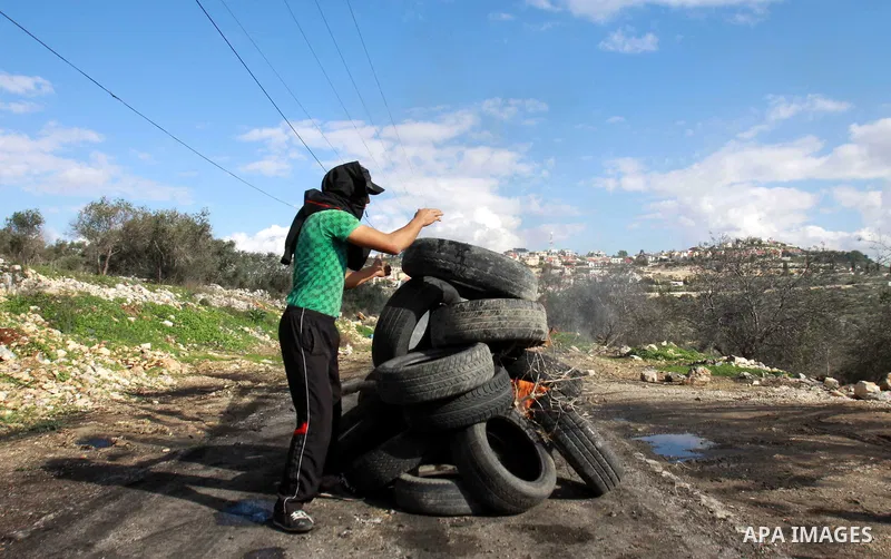A Palestinian protester burns tyres as clashes broke out with Israeli soldiers during a demonstration against the expropriation of Palestinian land by Israel in the village of Kfar Qaddum, near the occupied West Bank cit...