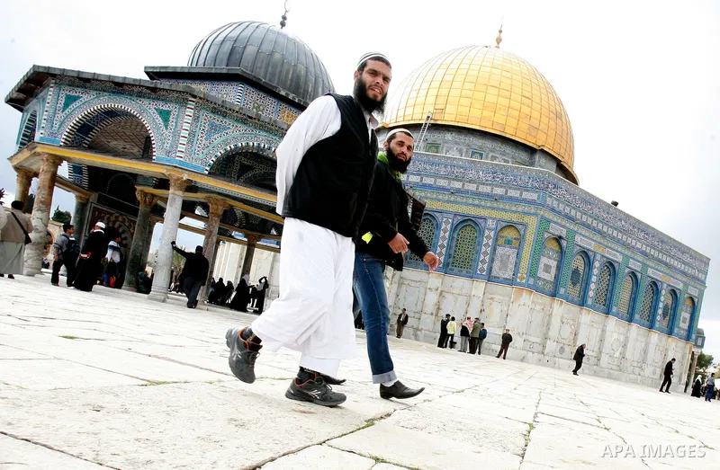 Palestinian and foreign worshippers walk in front of the Dome of the Rock mosque following Friday prayer at al-Aqsa mosque, Islam's third holiest site, on December 14, 2012, in the old city of Jerusalem. Photo by Mahfouz...