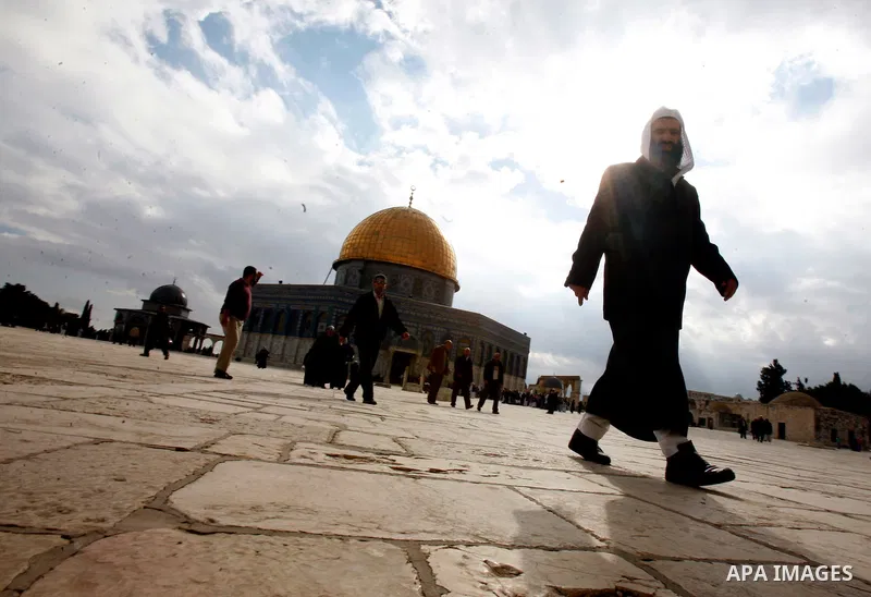 Palestinian and foreign worshippers walk in front of the Dome of the Rock mosque following Friday prayer at al-Aqsa mosque, Islam's third holiest site, on December 14, 2012, in the old city of Jerusalem. Photo by Mahfouz...