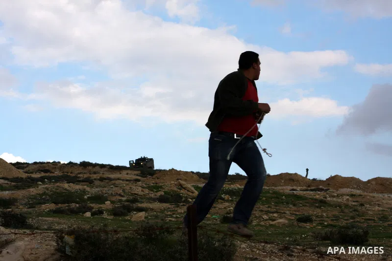 A Palestinian protester uses a slingshot to throw stones at Israeli soldiers after an attack by Israeli settlers on Palestinian homes in village of Urif near the west bank city of Nablus on Dec. 15, 2012 . Photo by Nedal...