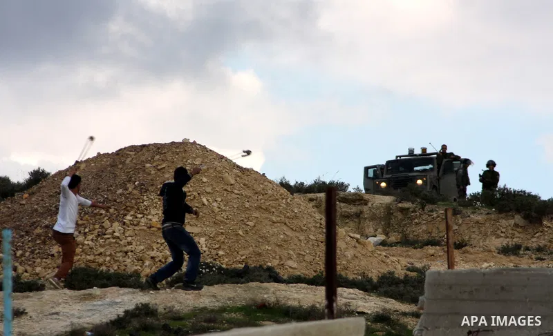 Palestinian protesters uses a slingshot to throw stones at Israeli soldiers after an attack by Israeli settlers on Palestinian homes in village of Urif near the west bank city of Nablus on Dec. 15, 2012 . Photo by Nedal...