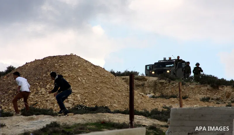 Palestinian protesters uses a slingshot to throw stones at Israeli soldiers after an attack by Israeli settlers on Palestinian homes in village of Urif near the west bank city of Nablus on Dec. 15, 2012 . Photo by Nedal...