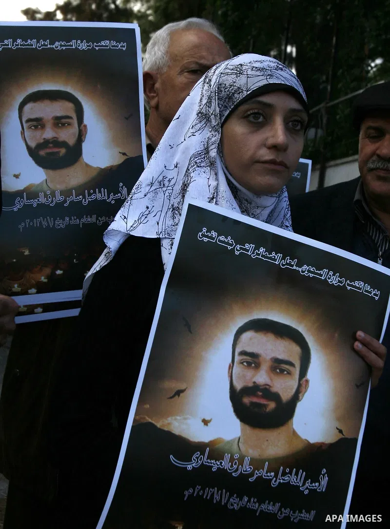 Palestinian protesters hold portraits of Samer Issawi, a Palestinian prisoner held in an Israeli jail and on hunger strike since August 1, during a solidarity sit-in outside the Red Cross offices in Jerusalem, on Dec. 15...