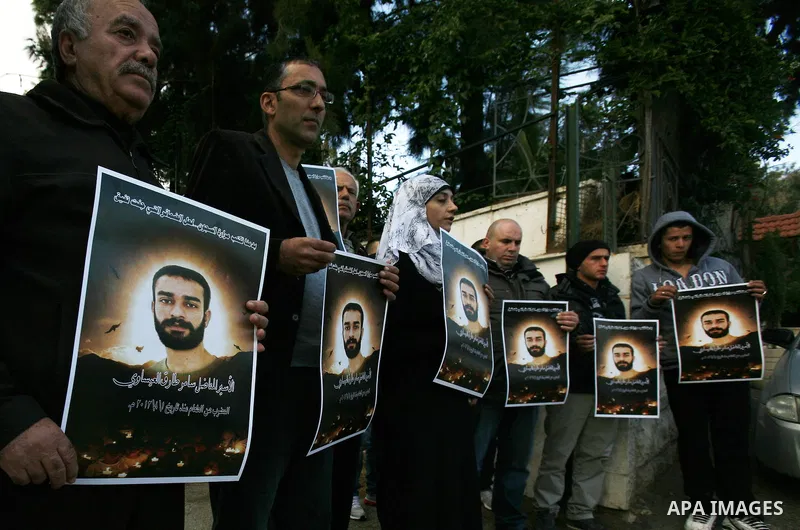 Palestinian protesters hold portraits of Samer Issawi, a Palestinian prisoner held in an Israeli jail and on hunger strike since August 1, during a solidarity sit-in outside the Red Cross offices in Jerusalem, on Dec. 15...