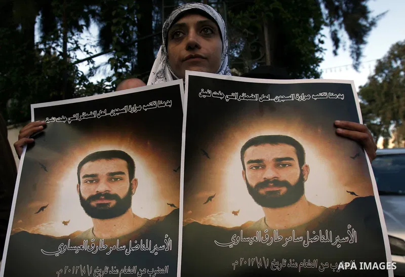 Palestinian protesters hold portraits of Samer Issawi, a Palestinian prisoner held in an Israeli jail and on hunger strike since August 1, during a solidarity sit-in outside the Red Cross offices in Jerusalem, on Dec. 15...
