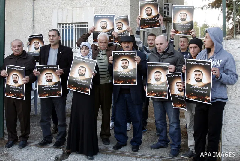 Palestinian protesters hold portraits of Samer Issawi, a Palestinian prisoner held in an Israeli jail and on hunger strike since August 1, during a solidarity sit-in outside the Red Cross offices in Jerusalem, on Dec. 15...