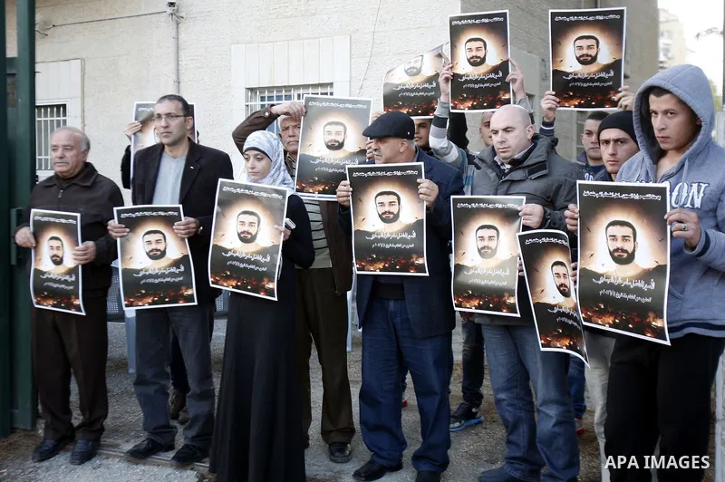 Palestinian protesters hold portraits of Samer Issawi, a Palestinian prisoner held in an Israeli jail and on hunger strike since August 1, during a solidarity sit-in outside the Red Cross offices in Jerusalem, on Dec. 15...