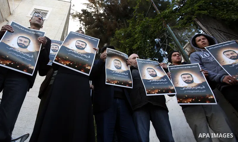 Palestinian protesters hold portraits of Samer Issawi, a Palestinian prisoner held in an Israeli jail and on hunger strike since August 1, during a solidarity sit-in outside the Red Cross offices in Jerusalem, on Dec. 15...