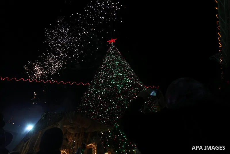 Palestinians celebrate the lighting of the Christmas tree in Manger Square, outside the Church of the Nativity, in the West Bank biblical town of Bethlehem, the traditional birthplace of Jesus as preparations for Christm...