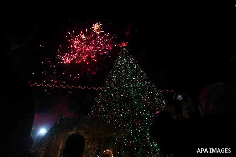 Palestinians celebrate the lighting of the Christmas tree in Manger Square, outside the Church of the Nativity, in the West Bank biblical town of Bethlehem, the traditional birthplace of Jesus as preparations for Christm...