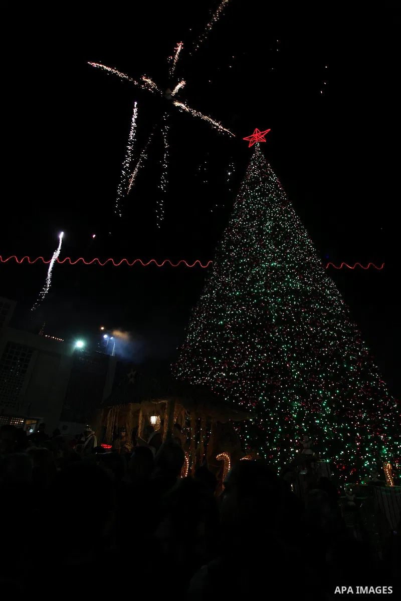 Palestinians celebrate the lighting of the Christmas tree in Manger Square, outside the Church of the Nativity, in the West Bank biblical town of Bethlehem, the traditional birthplace of Jesus as preparations for Christm...
