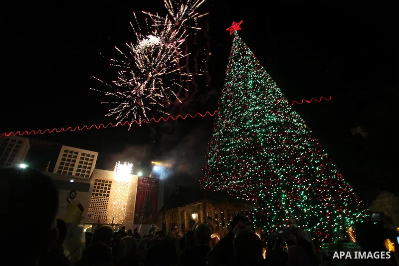Palestinians celebrate the lighting of the Christmas tree in Manger Square, outside the Church of the Nativity, in the West Bank biblical town of Bethlehem, the traditional birthplace of Jesus as preparations for Christm...