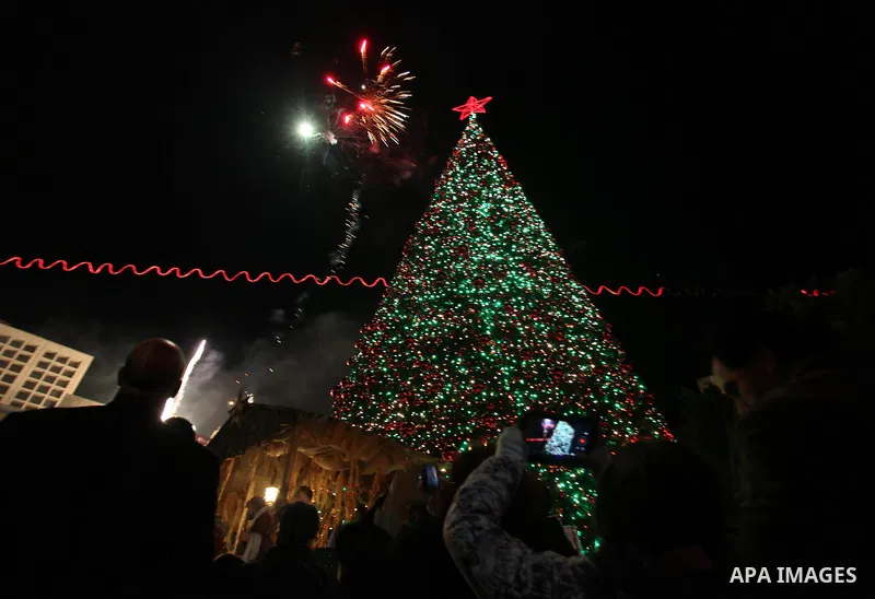Palestinians celebrate the lighting of the Christmas tree in Manger Square, outside the Church of the Nativity, in the West Bank biblical town of Bethlehem, the traditional birthplace of Jesus as preparations for Christm...
