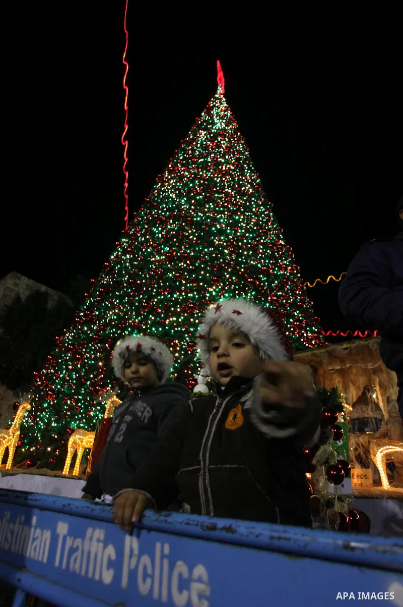 Palestinians celebrate the lighting of the Christmas tree in Manger Square, outside the Church of the Nativity, in the West Bank biblical town of Bethlehem, the traditional birthplace of Jesus as preparations for Christm...