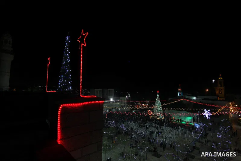 Palestinians celebrate the lighting of the Christmas tree in Manger Square, outside the Church of the Nativity, in the West Bank biblical town of Bethlehem, the traditional birthplace of Jesus as preparations for Christm...